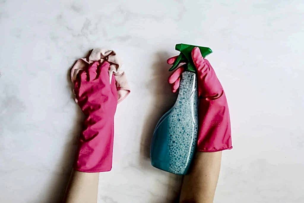 gloved hand holding cleaning supplies