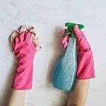 gloved hand holding cleaning supplies