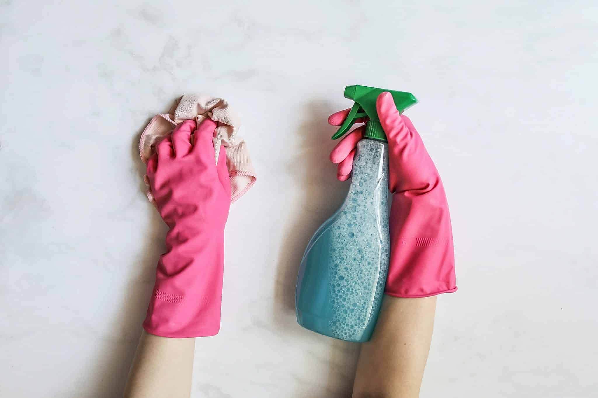 gloved hand holding cleaning supplies